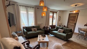 A cozy living room with two green sofas, a wooden coffee table, and a fluffy white dog. - La Dorbluche duplex apartment 10-11 person, 2km from the slopes (Aime-la-Plagne)