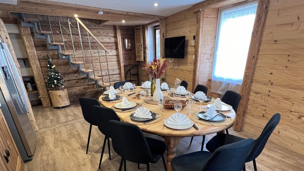A dining area with a wooden table set for four, surrounded by black chairs. A small Christmas tree is visible in the corner. - La Dorbluche duplex apartment 10-11 person, 2km from the slopes (Aime-la-Plagne)