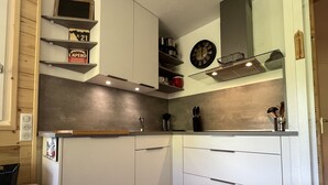 Ett modernt kök med vita skåp, en bänkskiva i trä och en klocka på väggen.