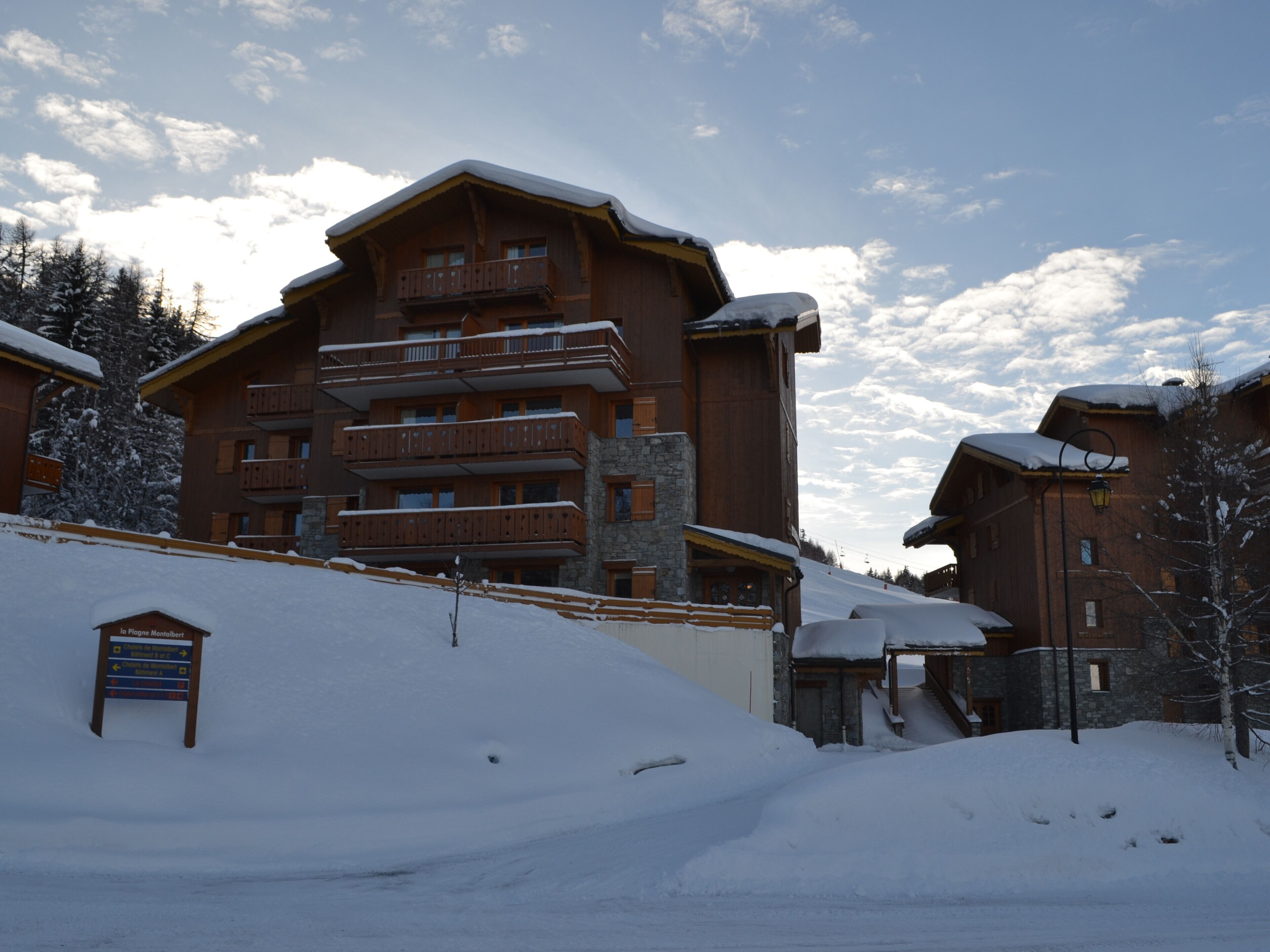 A large wooden building with multiple balconies and a sign indicating a ski resort.