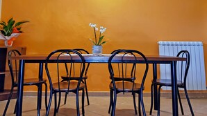 A dining area with a table and chairs, a wall-mounted light, and a radiator. - The Count's Vaults (Castro)