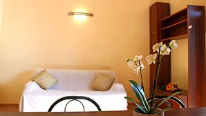 A room with a white sofa, a wooden table, and a potted orchid. - The Count's Vaults (Castro)