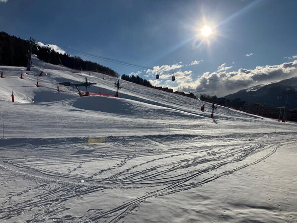 Pista de esquí nevada con telesillas y huellas.