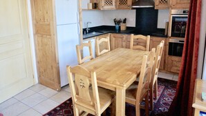 Uma cozinha com armários de madeira, uma geladeira branca e uma mesa de jantar com cadeiras.
