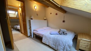 Ein Schlafzimmer mit einem Bett, einem Nachttisch aus Holz, einem kleinen Holztisch und einem an der Wand befestigten Regal.