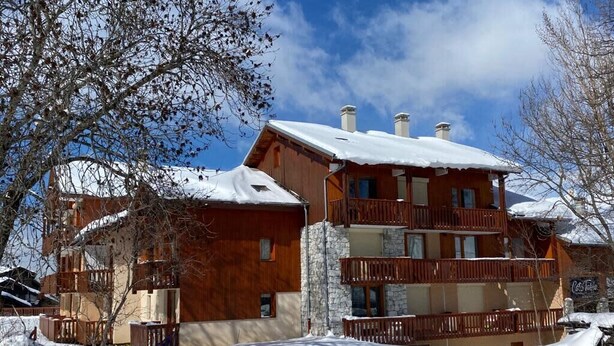 Eine Holzhütte mit mehreren Balkonen und einer Steinfassade, umgeben von Schnee.
