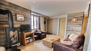 A cozy living room with a wood-burning stove, a sofa, a coffee table, and a TV.