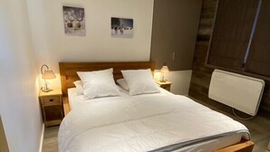 A neatly made bed with white linens, two bedside tables with lamps, and two wall-mounted artworks.
