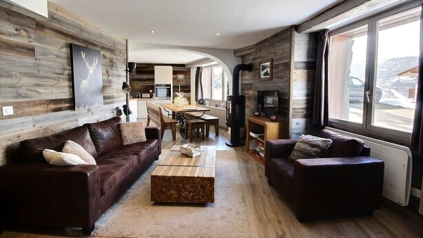 A modern living room with a fireplace, wooden walls, and a dining area.