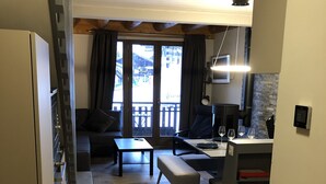 En kompakt opholdsstue med tekøkken, sofa, spisebord og bænk.