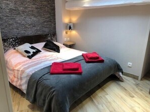 Un dormitorio con una cama, almohadas, una mesita de noche y una lámpara.