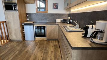 Une cuisine moderne avec des meubles en bois, un four encastré, un évier et une machine à café.