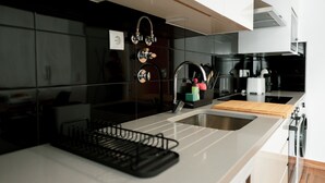 Una cocina moderna con un lavamanos de acero inoxidable, una tabla de cortar de madera y un escurreplatos negro.