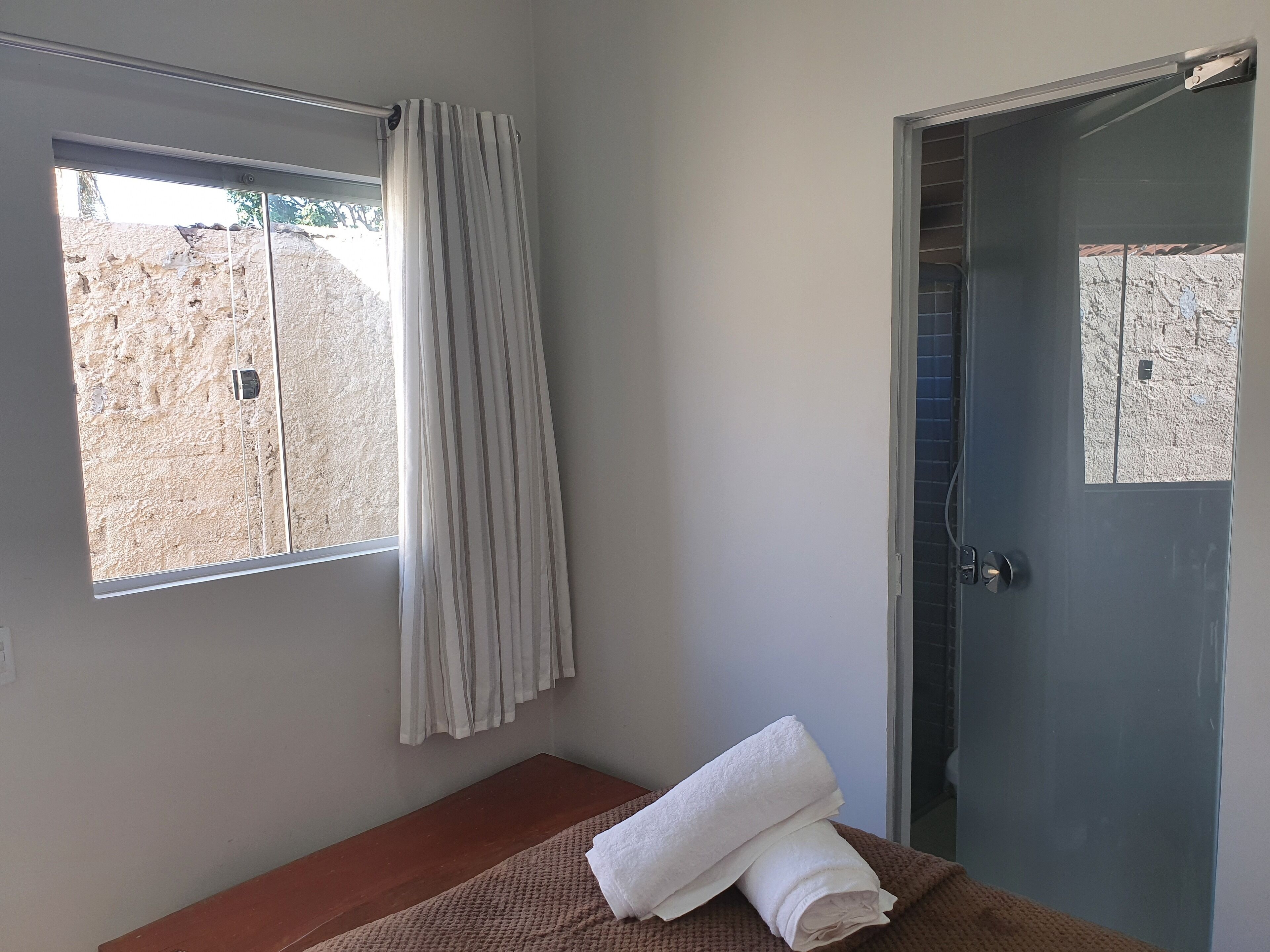 Une pièce avec un lit, une fenêtre avec des rideaux et une porte.