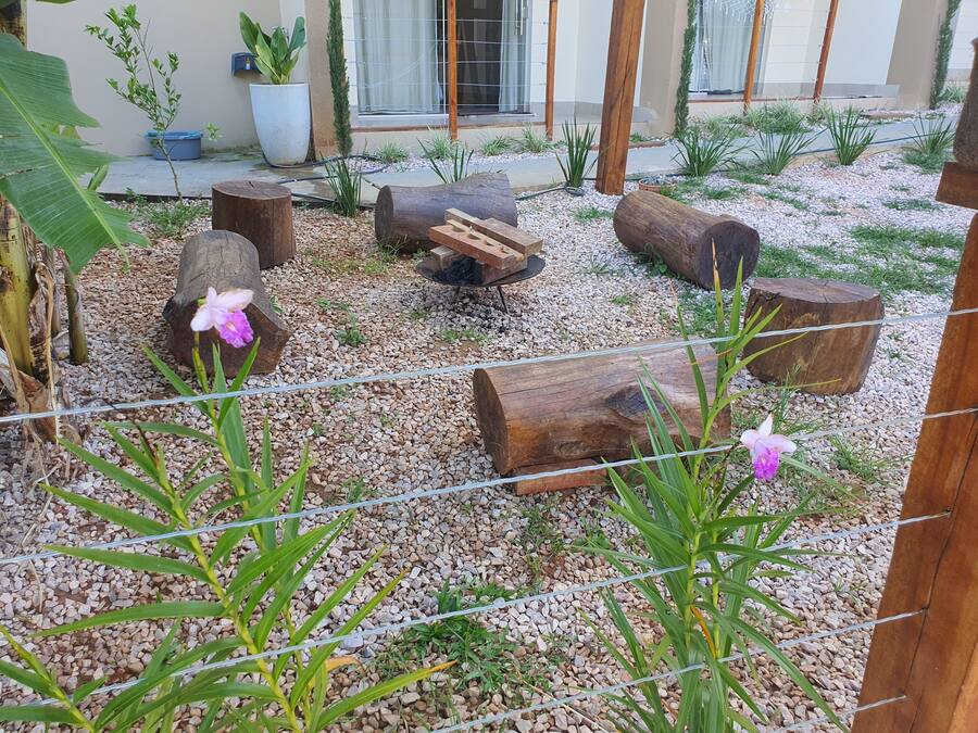 A garden with wooden logs, gravel, and potted plants.