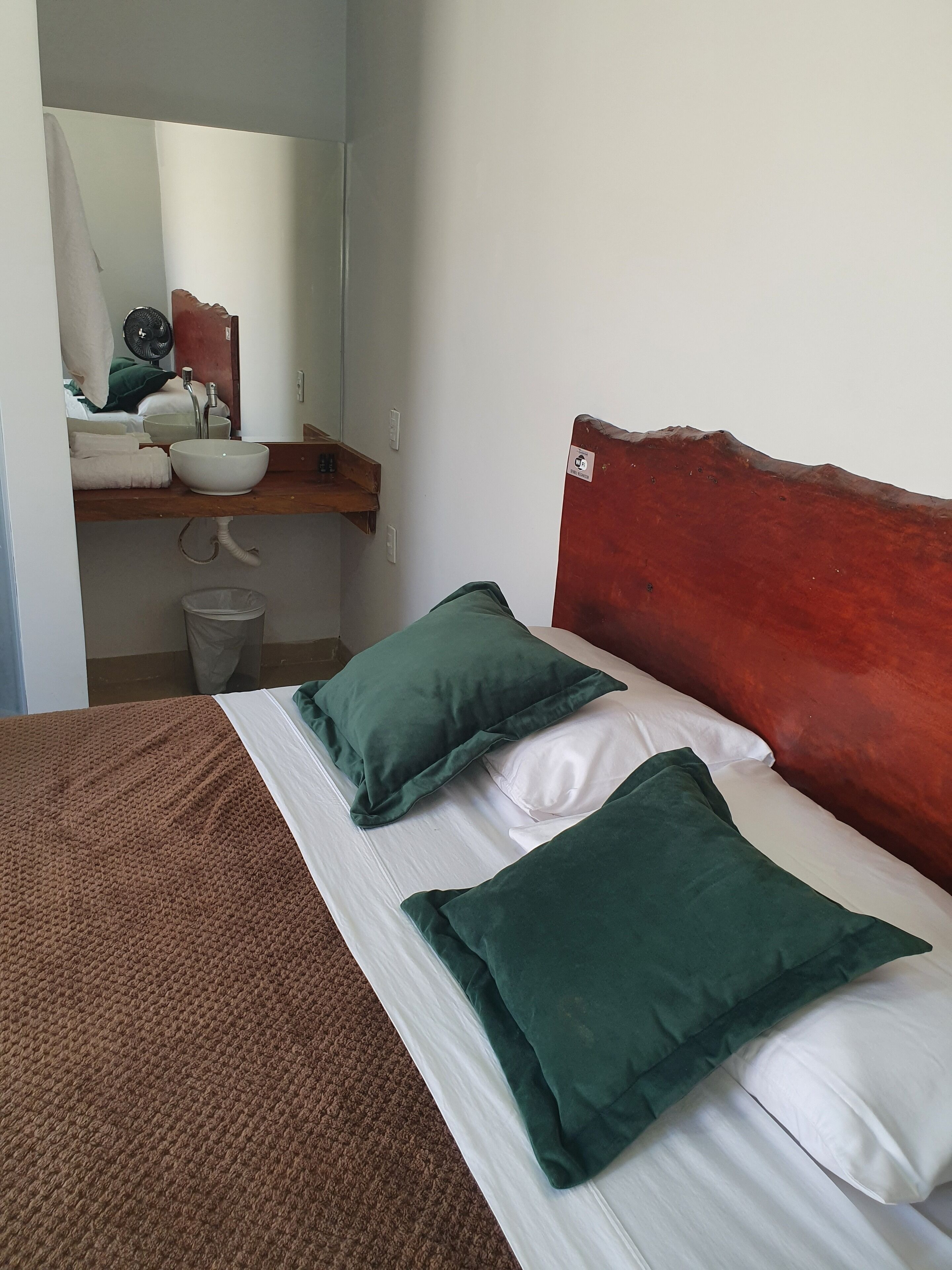 A bed with green pillows, a white pillow, and a brown blanket.