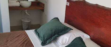 A bed with green pillows, a white pillow, and a brown blanket.