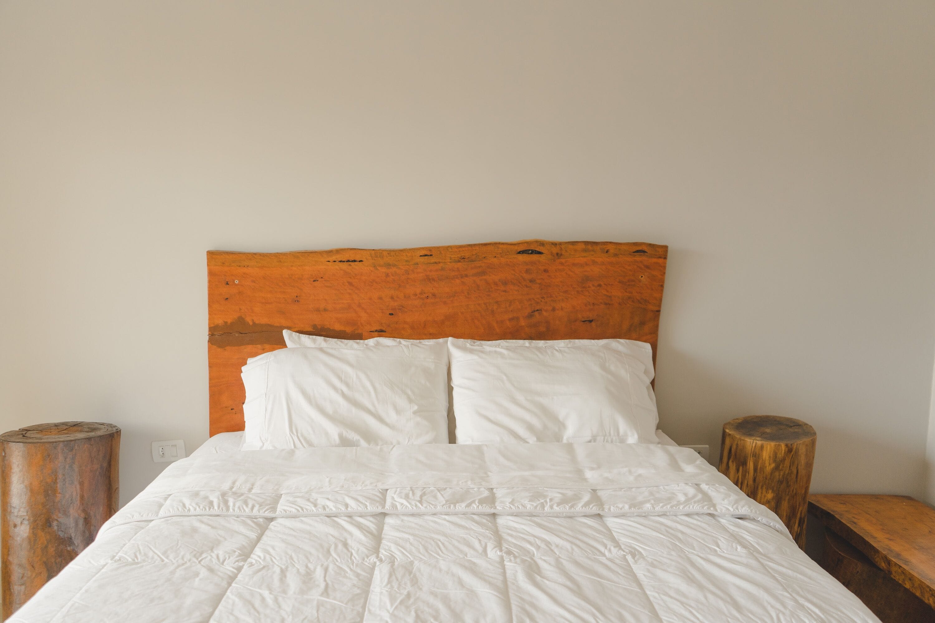 Un lit avec une literie blanche, une tête de lit en bois et deux tables de chevet en bois.