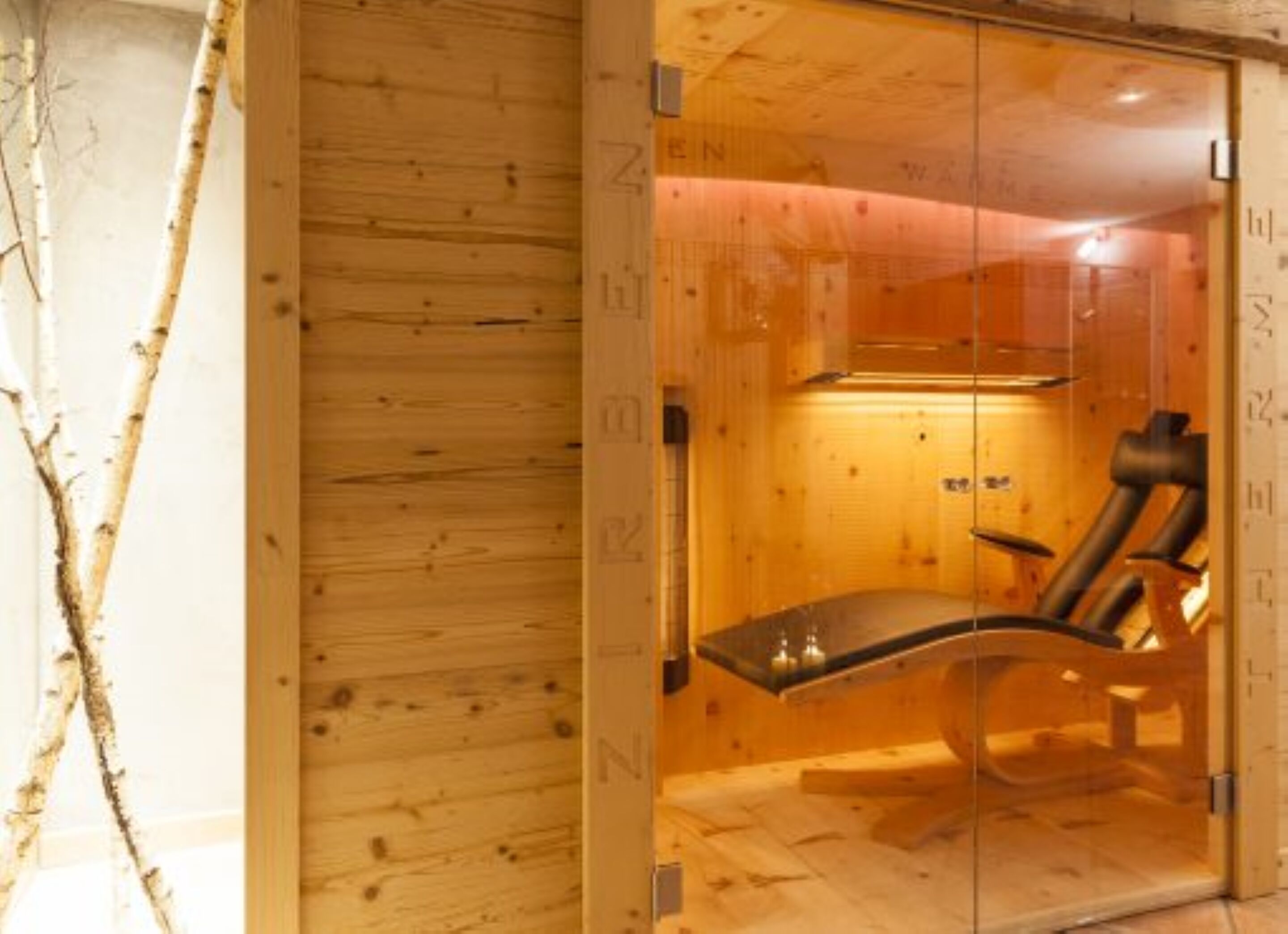 A wooden sauna room with a bench and a glass door.