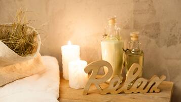 A wooden table with a white candle, two bottles of liquid, and a 'Relax' sign.
