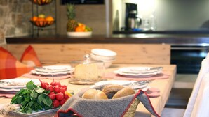 A dining table set with plates, a basket of bread, and a glass container of cheese. - Fiakerhof (Garmisch-Partenkirchen)