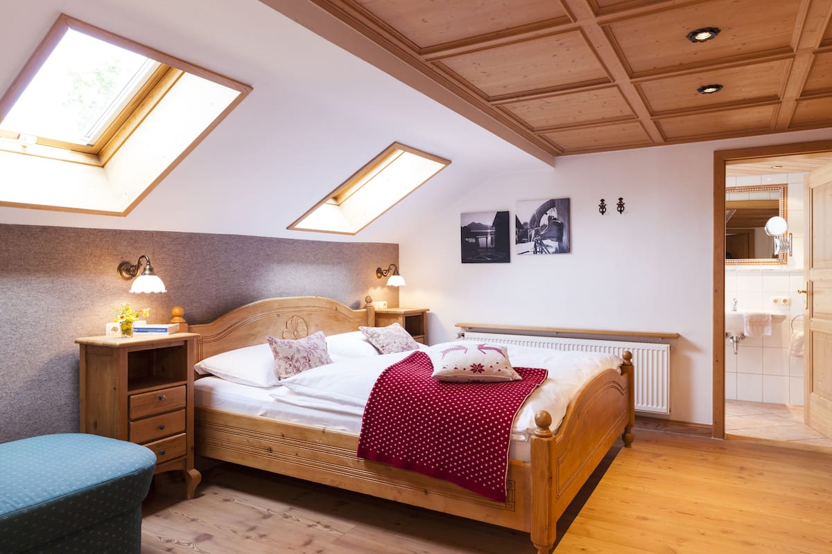 A bedroom with a wooden bed, skylights, a nightstand, and a bedside table with a lamp.