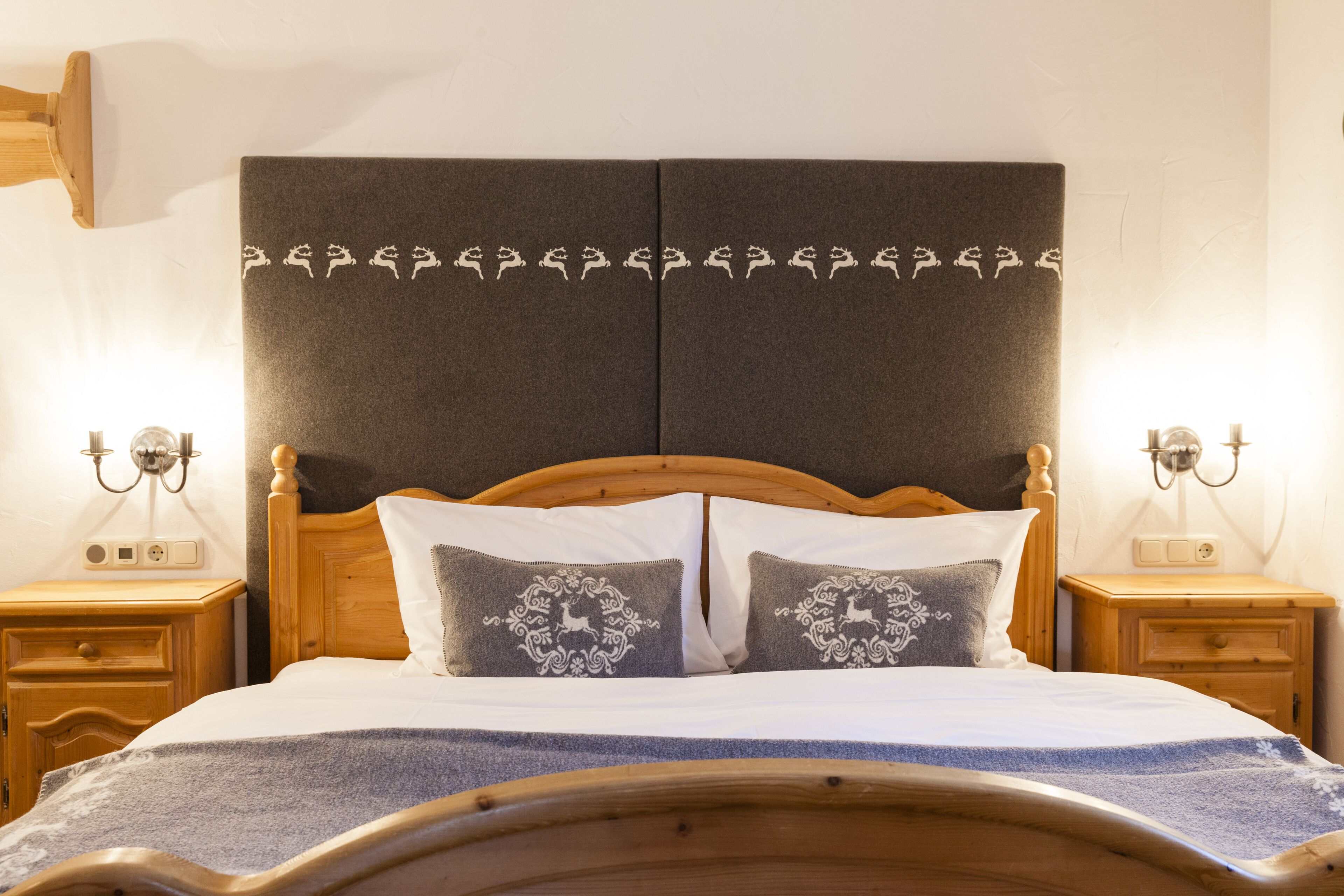 A neatly made bed with a wooden headboard, two bedside tables with lamps, and decorative pillows.
