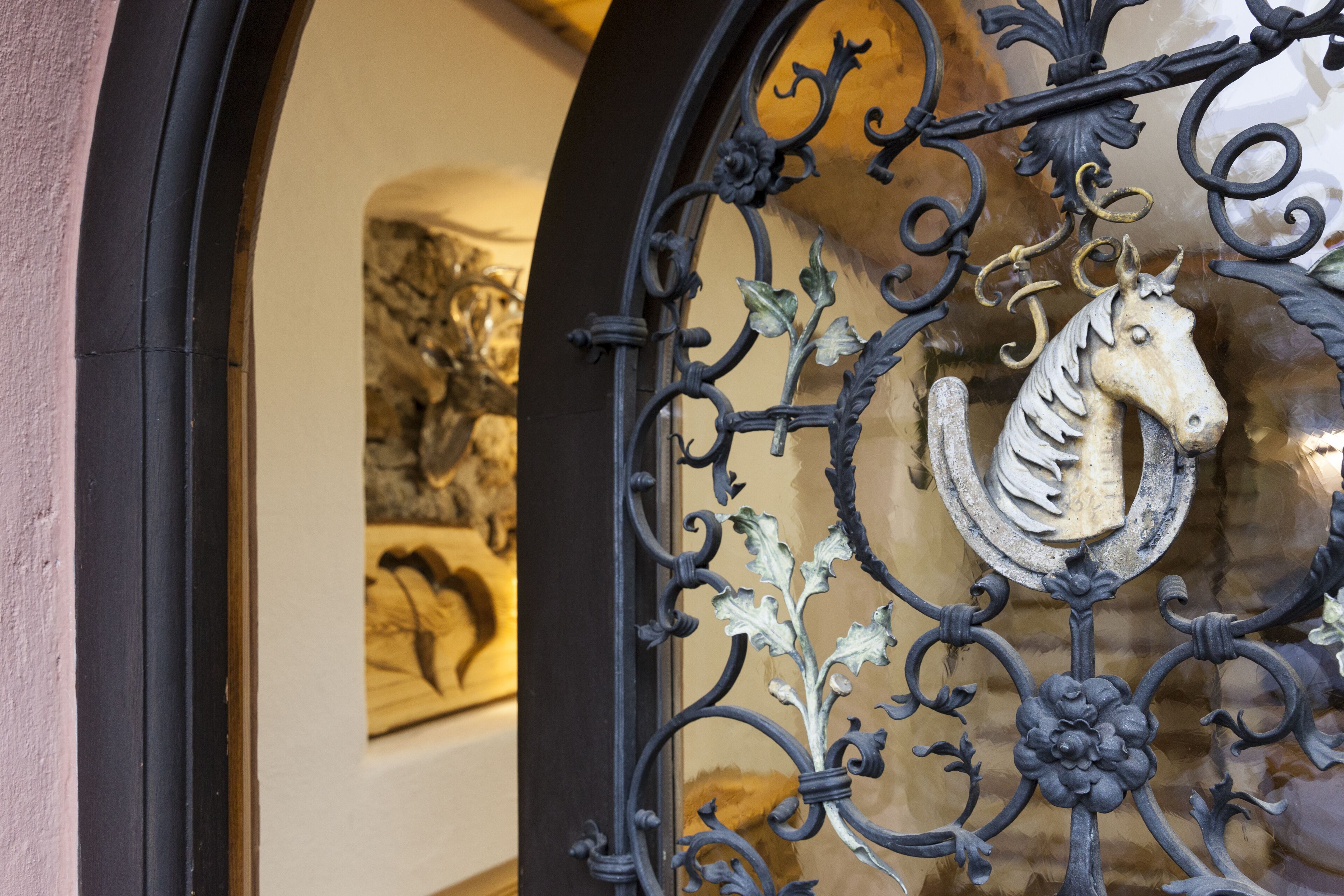 A wrought iron gate with a horse emblem, part of a building's entrance.
