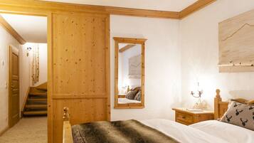 Un dormitorio con cabecero de madera, una mesita de noche con lámpara, un espejo y una escalera que lleva a otra habitación.
