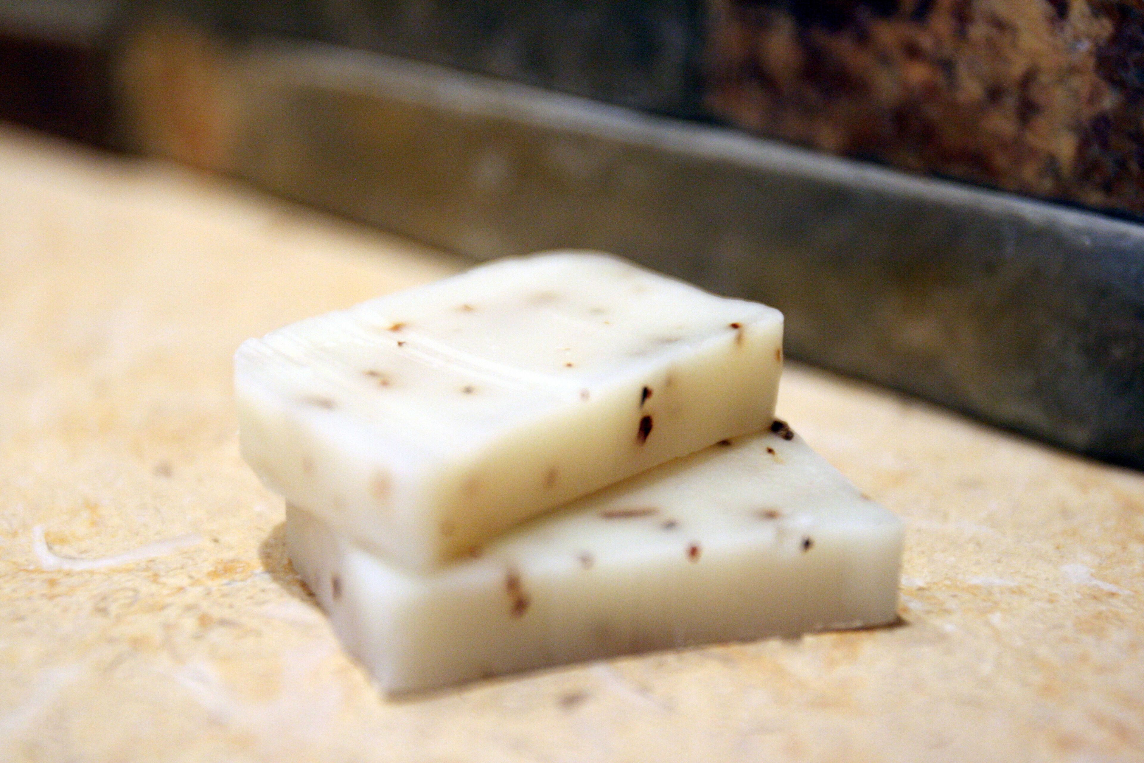 Two white bars with specks, possibly soap, on a textured surface.