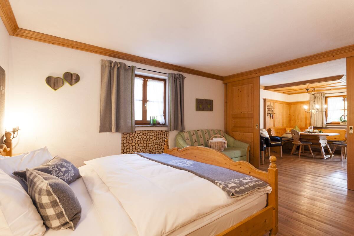 A cozy bedroom with a wooden bed, a small table, and a chair.