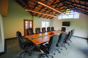 A conference room with a long table, multiple chairs, a ceiling fan, and a television on the wall.