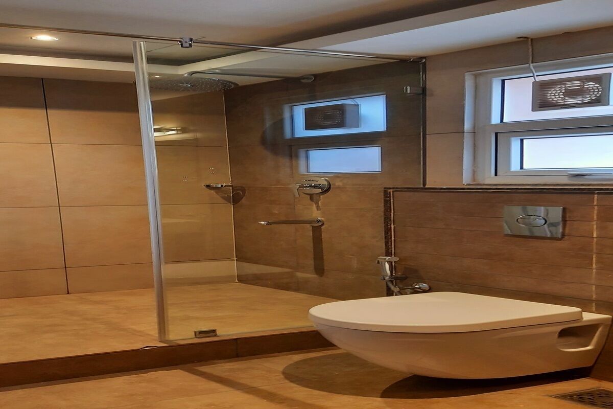 Une salle de bain moderne avec une douche à parois de verre, un lavabo blanc et une fenêtre équipée de stores.