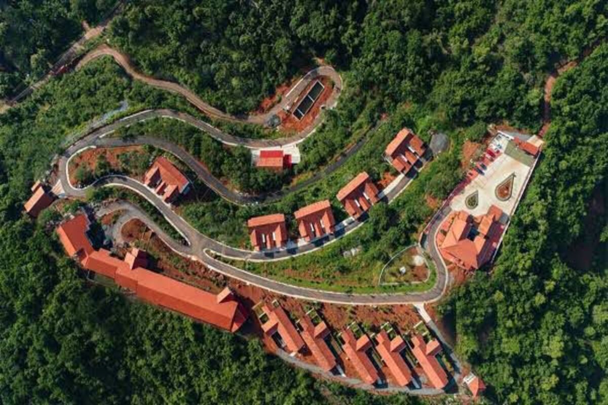 An aerial view of a resort with winding roads, red-roofed buildings, and lush greenery.