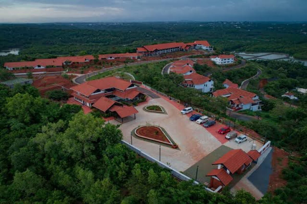 An aerial view of a resort with multiple buildings, a parking area, and a landscaped garden.