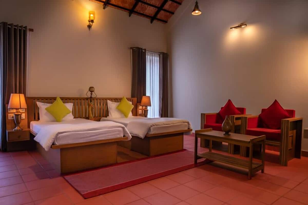 A hotel room with two beds, a red sofa, a wooden coffee table, and a red rug.