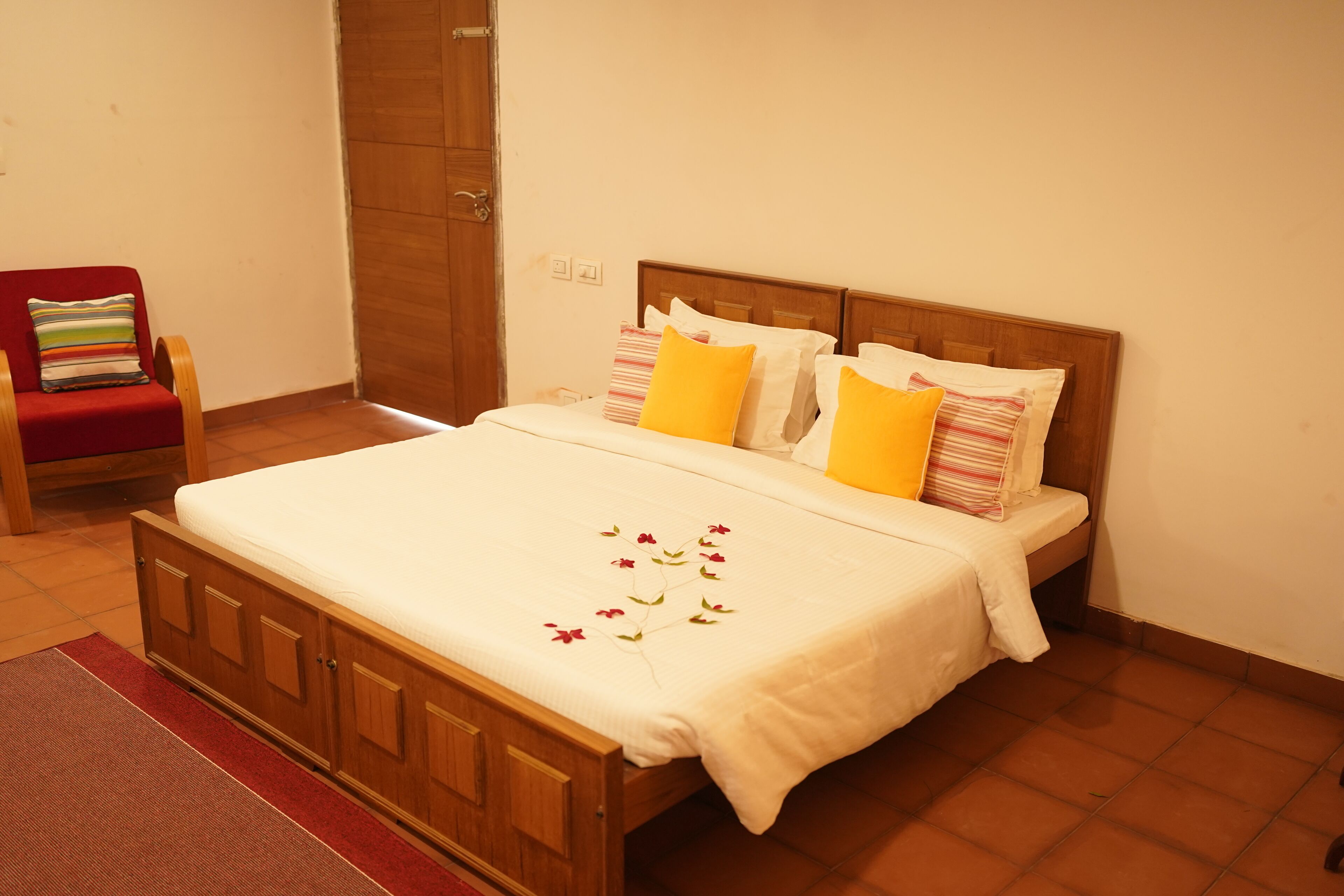 A neatly made bed with a floral bedspread, a wooden headboard, and two pillows with striped patterns.