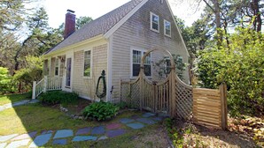 A single-story house with a sloped roof, a front porch, and a wooden gate.