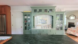 A kitchen with a marble island, a refrigerator, and a dining table.