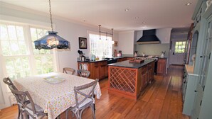 A spacious kitchen with wooden flooring, a dining area with a table and chairs, and a large island with a built-in sink.