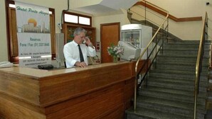 A hotel reception desk with a wooden counter, a telephone, and a poster advertising reservations. - Hotel Porto Alegre (Porto Alegre)