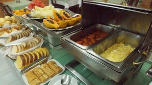 A buffet with various food items including fruits, pastries, and a meat dish. - Hotel Porto Alegre (Porto Alegre)
