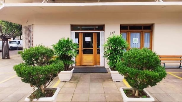 Hotel Porto Alegre with a green sign, a wooden door, and potted plants in front. - Hotel Porto Alegre (Porto Alegre)