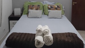 Une chambre d’hôtel avec un lit, des oreillers, un tableau représentant une scène de plage et une porte.