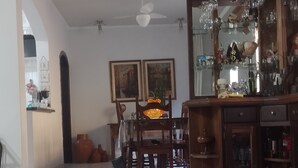 Un coin repas avec une table et des chaises en bois, une vitrine contenant des objets décoratifs et un ventilateur de plafond.