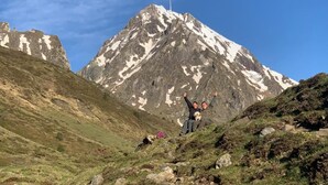 Eine Berglandschaft mit zwei Personen, die auf einer grasbewachsenen Anhöhe feiern.