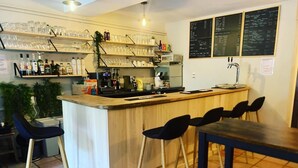 Eine Bar mit Hockern, einer Theke und Regalen mit Gläsern und Flaschen.