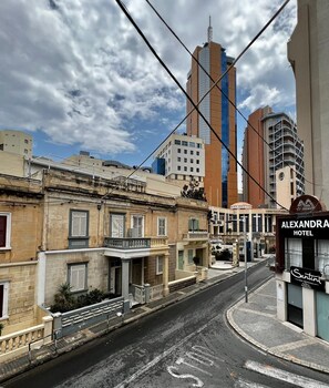 A street view with buildings, including a hotel named 'Alexandra Hotel' and a restaurant 'Santini'. - Bookarest Hostel Malta (St. Julian's)