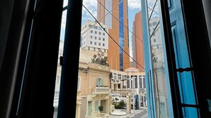 Janela com vista para edifícios altos e uma rua.