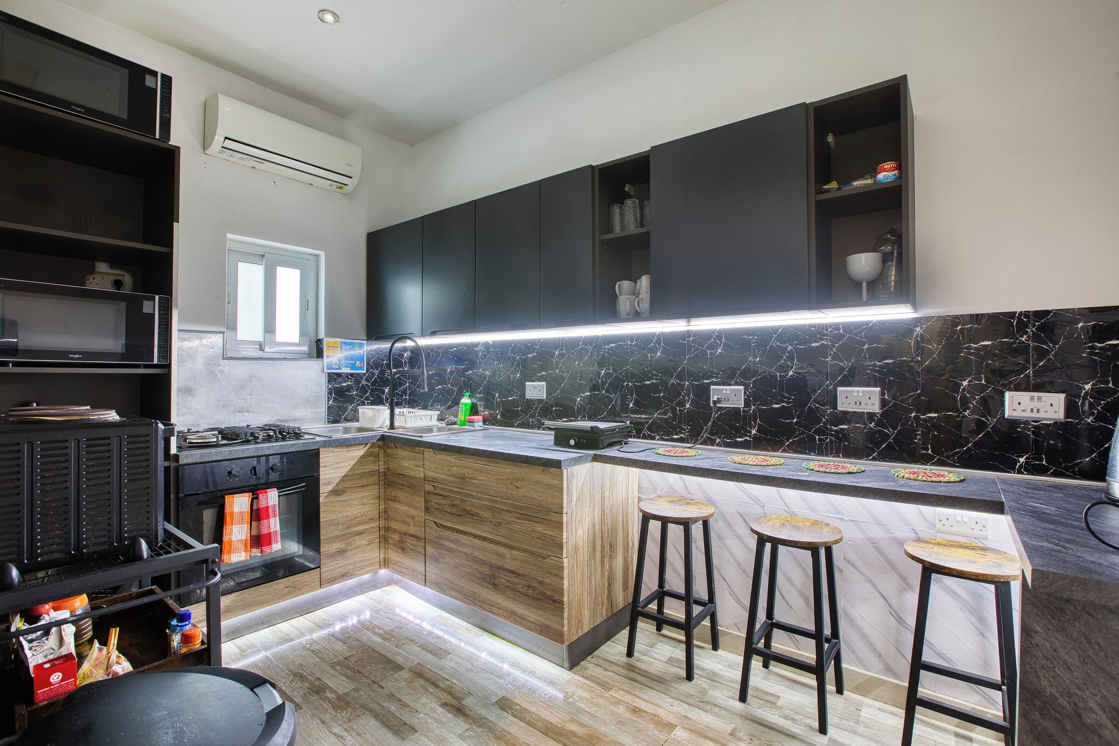 A modern kitchen with a black countertop, wooden cabinets, and a marble backsplash.